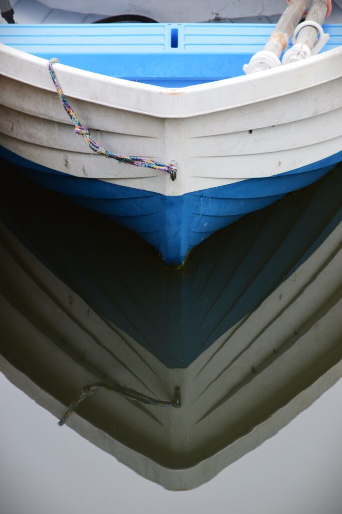 Close-up of a white and blue rowboat reflected in calm waters at Northport Harbor.